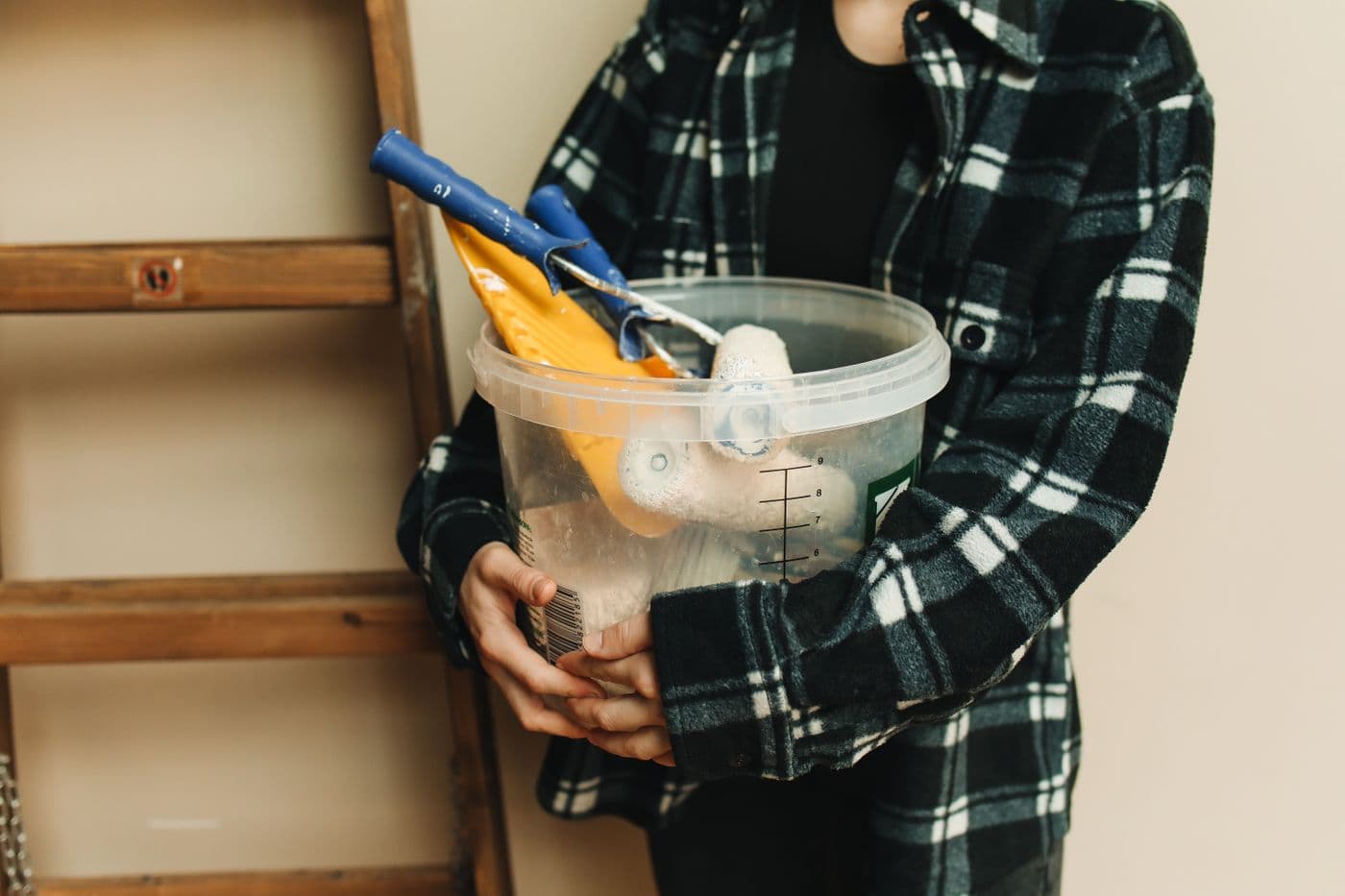 A bucket stocked with paint rollers and home repair tools